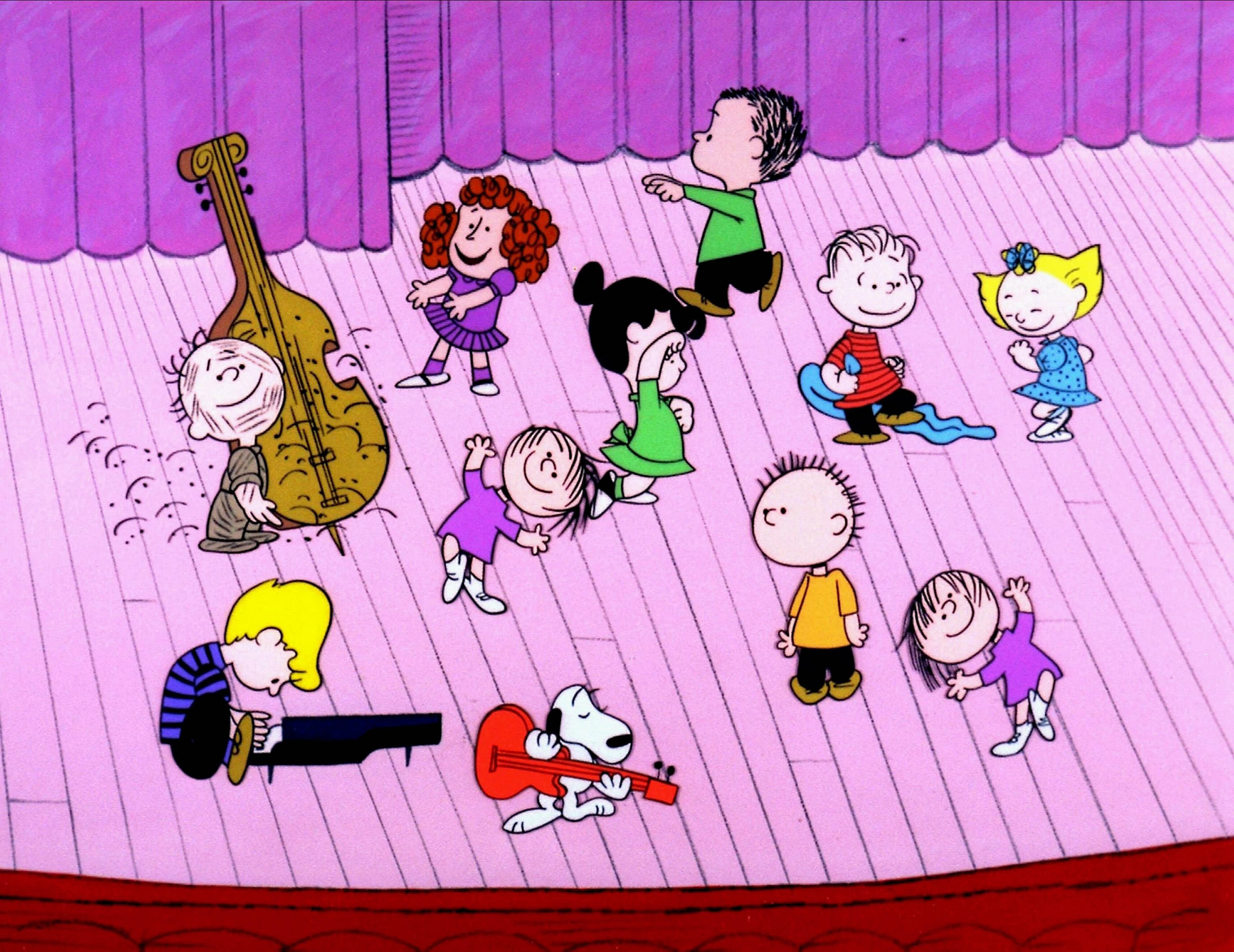 An image from the dance scene in a Charlie brown Christmas is shown. Pigpen is playing an upright bass, schroeder is playing piano and Snoopy is playing guitar