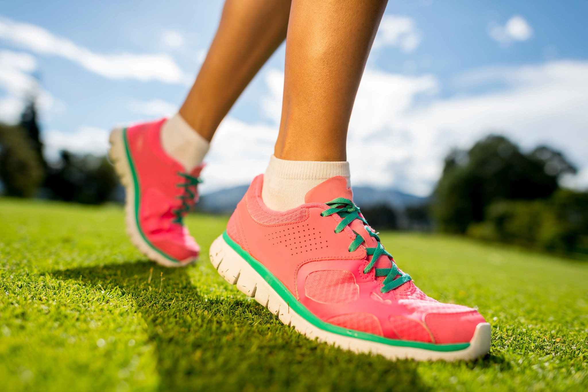Close-up of athletic shoes moving across grass on golf course