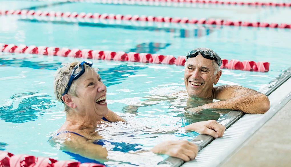Exercise is one of the most powerful ways to support your brain health A man and woman hanging on the wall inside an indoor pool