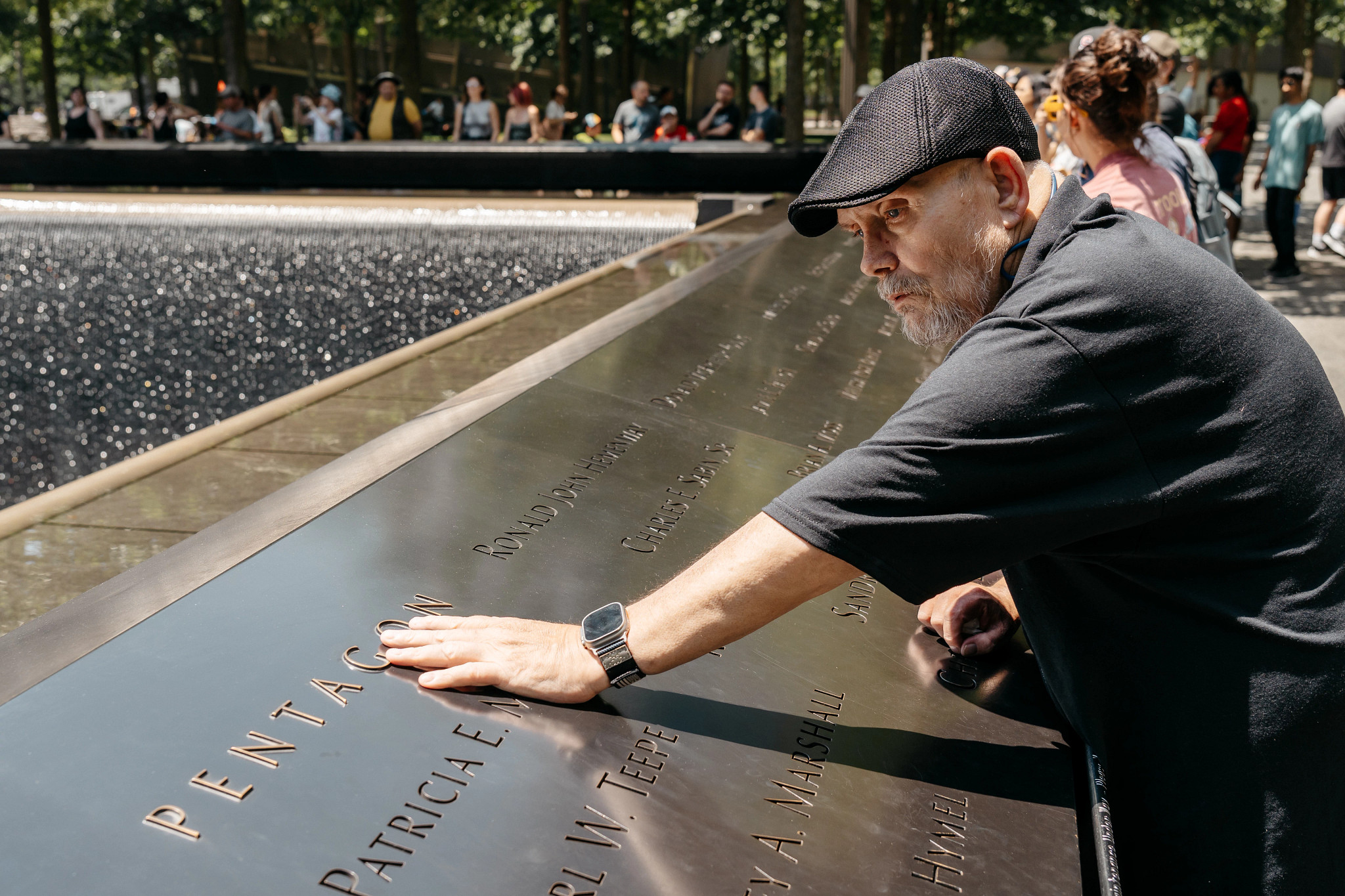 greg ryan placing his hand on the wall of the 9 11 memorial fountain