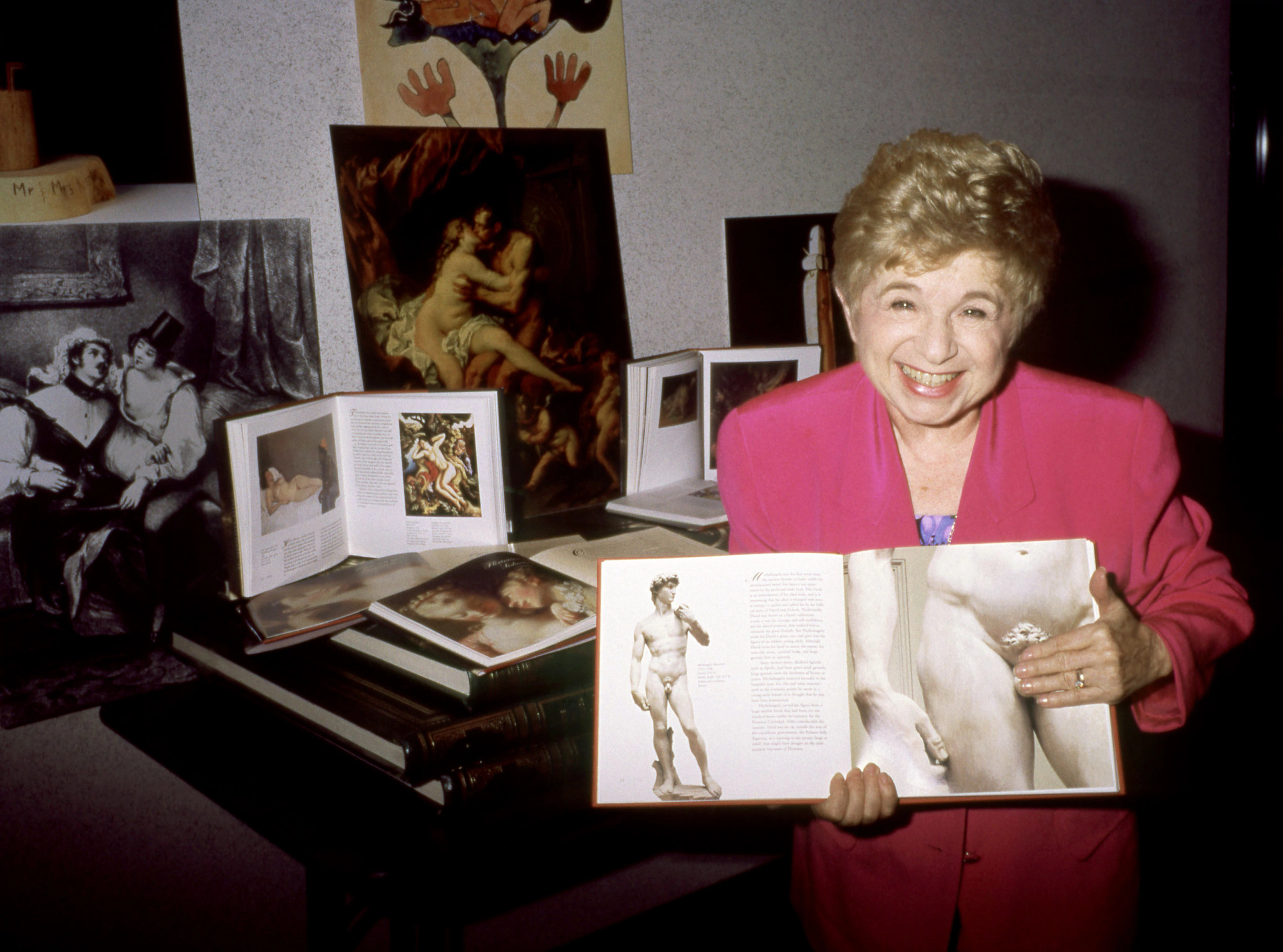 dr ruth stands by a table with books