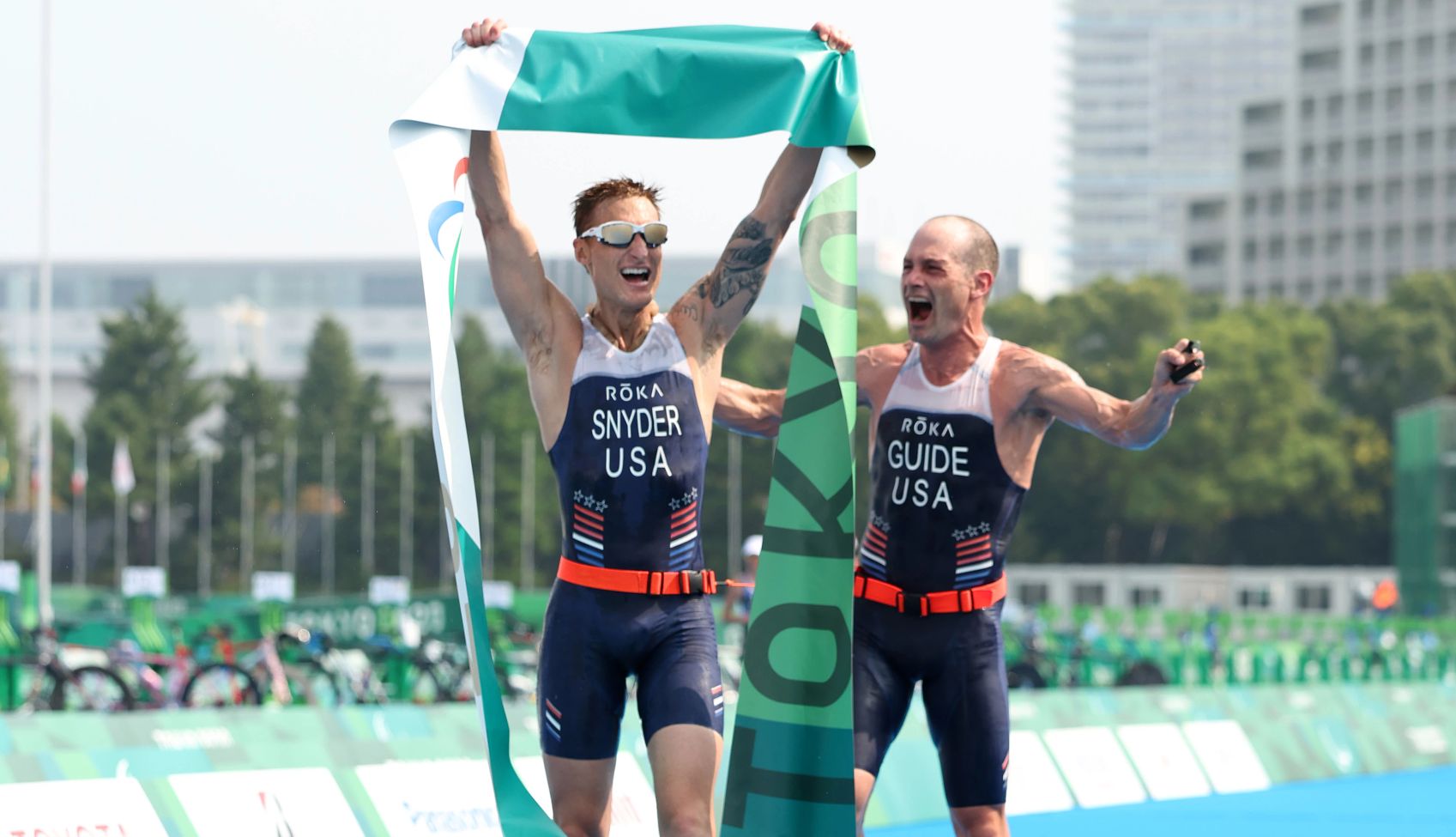 Brad Snyder and guide Greg Billington brad snyder holds a green banner over his head as he celebrates with guide greg billington after winning a triathalon