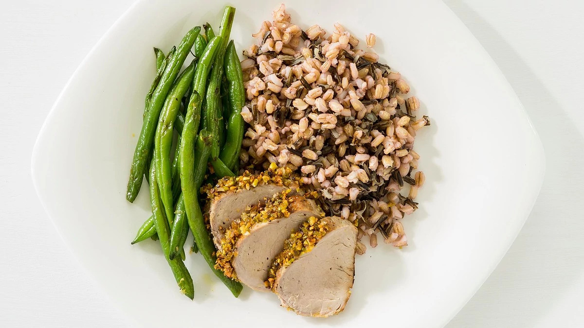 A close-up view of pistachio-crusted pork tenderloin on a plate