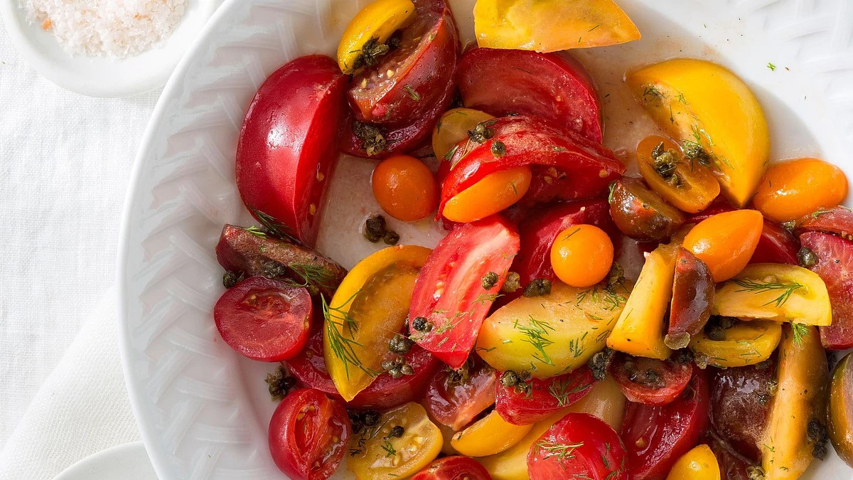 A close-up view of heirloom tomato salad with fried capers on a plate