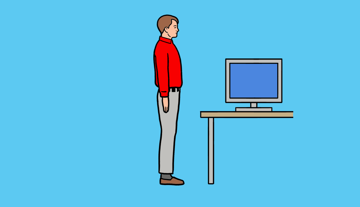A man does a standing push-up with his hands on the edge of a desk.