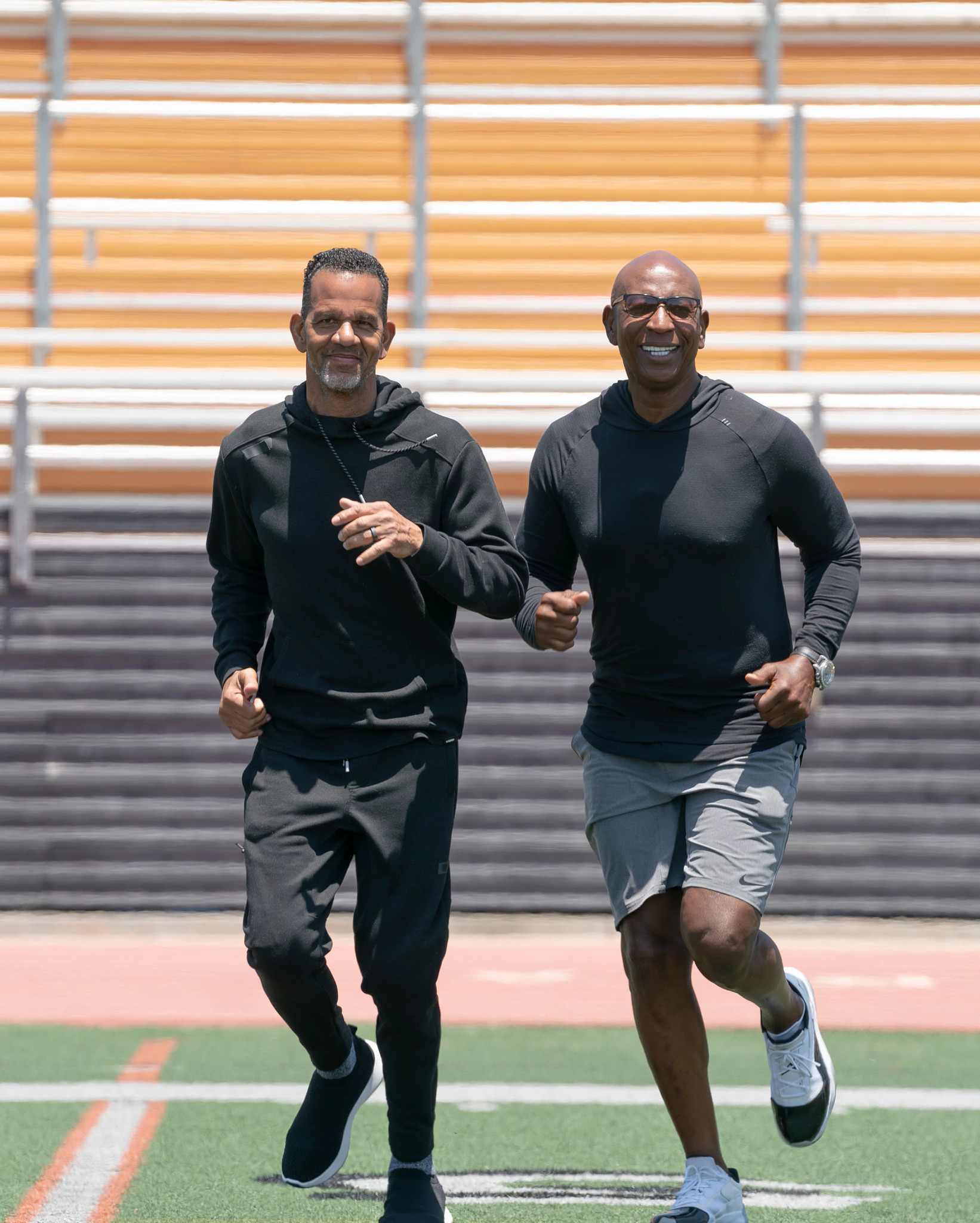Former NFL players Andre Reed and Eric Dickerson running together on an athletic field