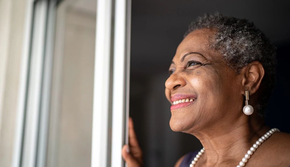 Mindfulness may help open up some space for yourself with what is A woman smiling and looking at the view outside