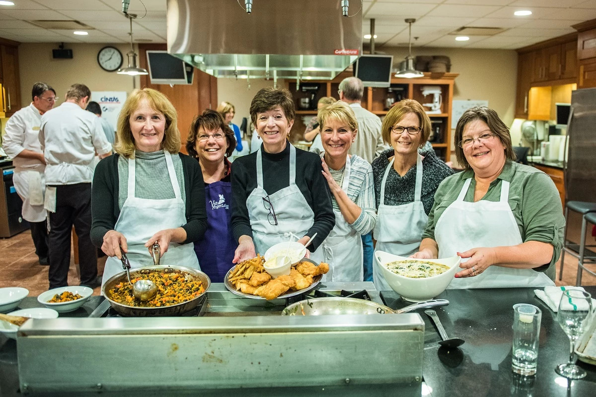 a group of women posing with food during a cooking class