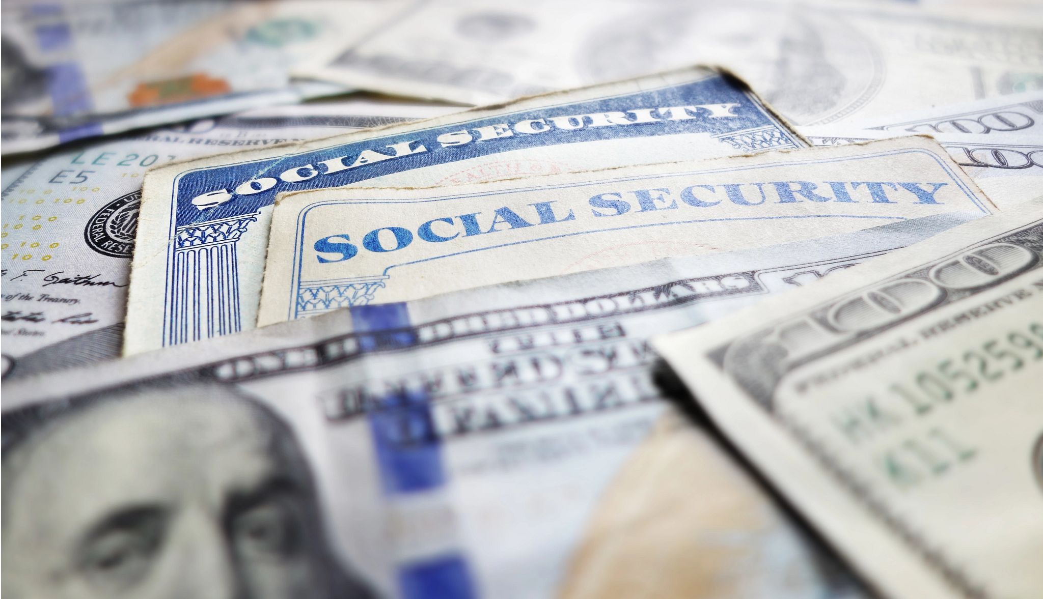 Social Security cards laid out together with hundred dollar bills Social Security cards laid out together with hundred dollar bills