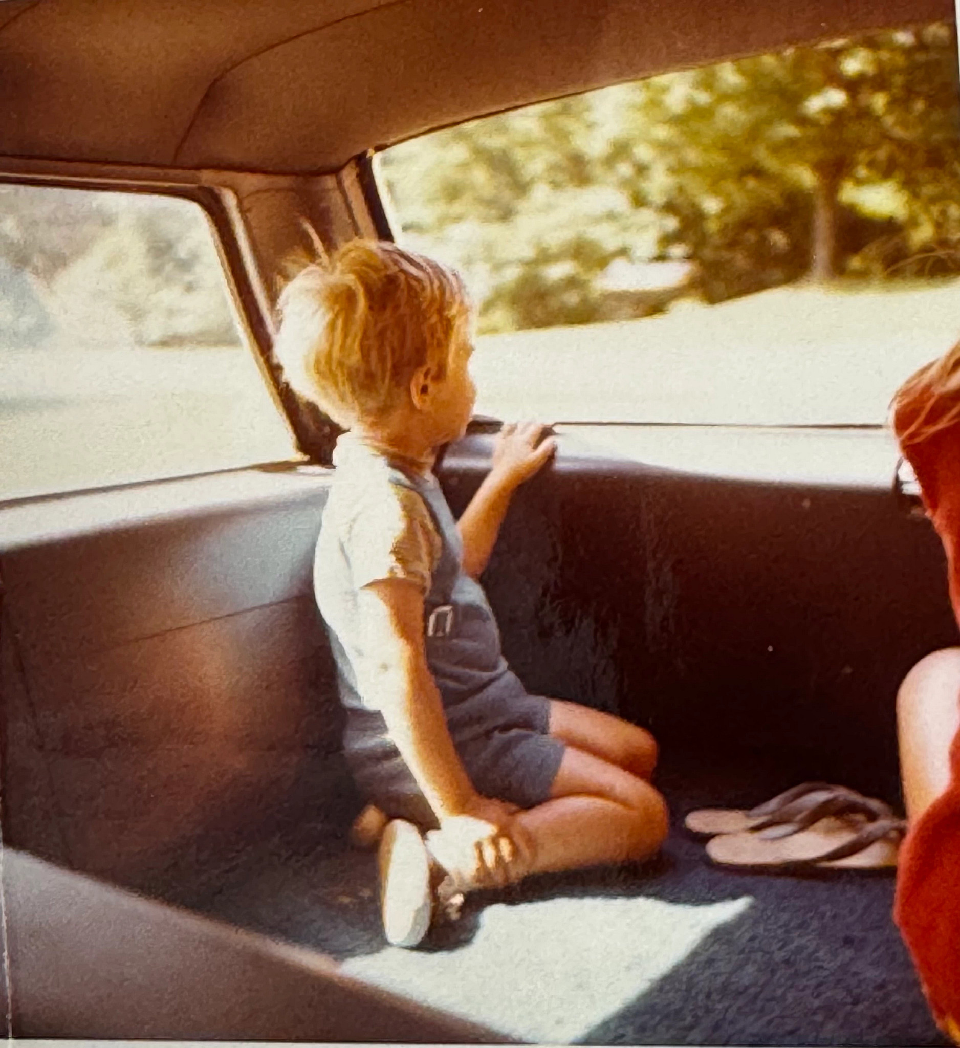 a vintage photo of a boy in the backseat of a car