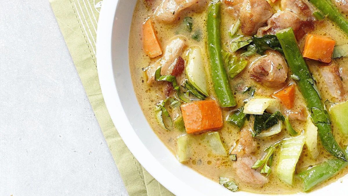 A close-up view of green chicken curry in a bowl