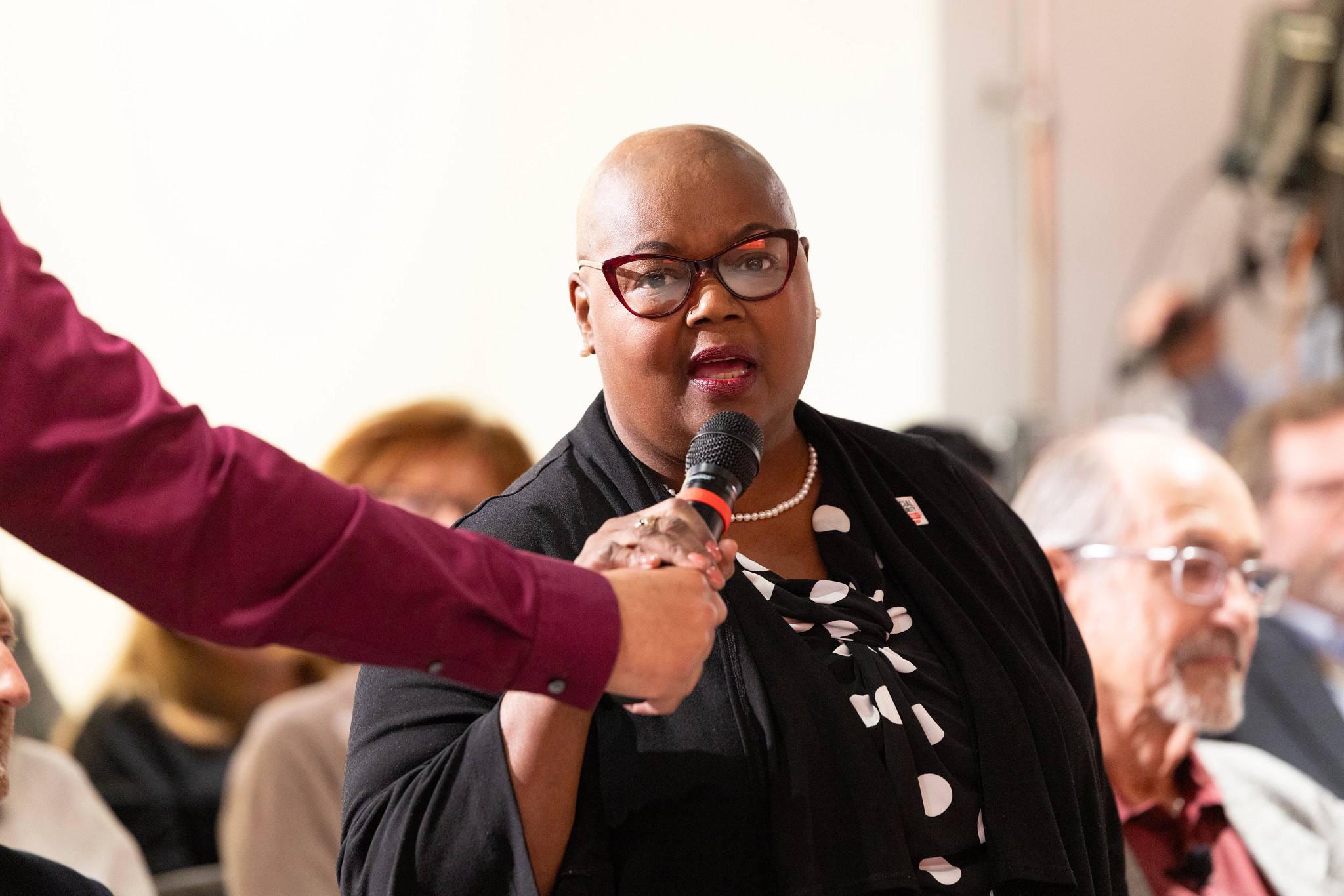 a woman speaks into a microphone in front of a crowd