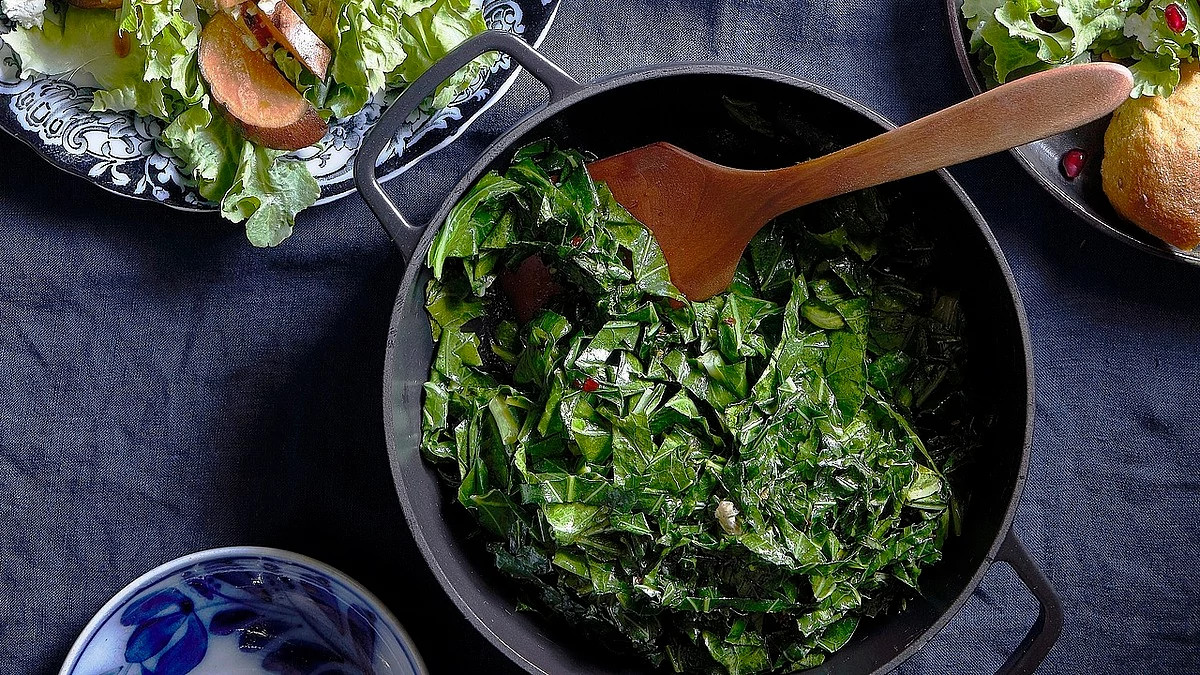 A close-up view of sweet and spicy steam-fried collard greens in a pot