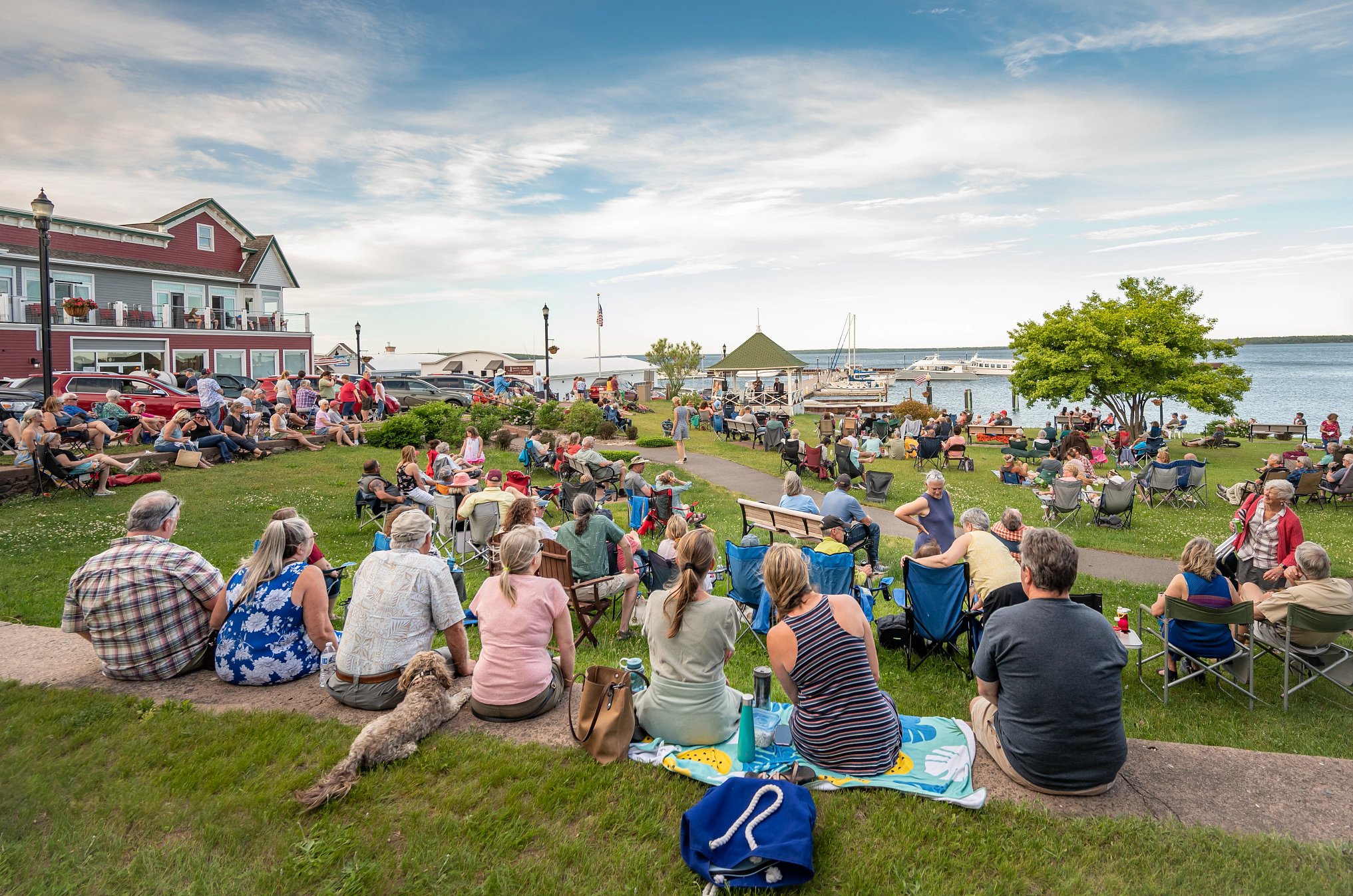 Great Lakes Getaways a large crowd sitting in a grassy area near a lake