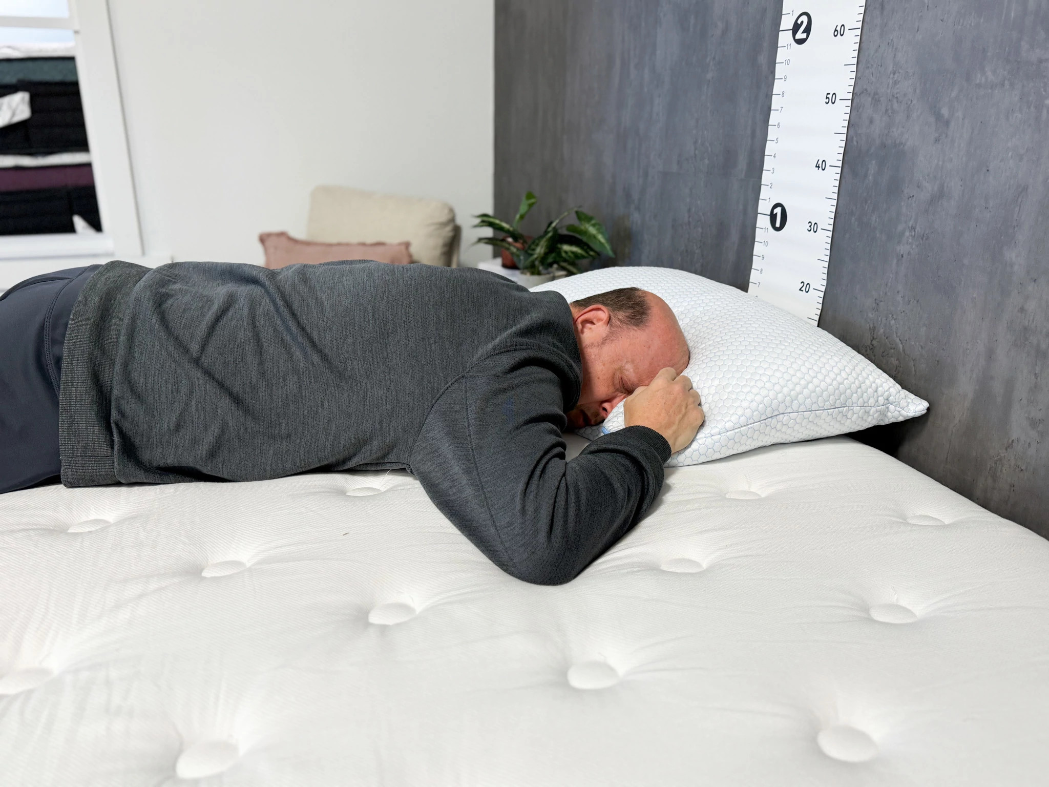  A man sleeping on his stomach on a bed with his head resting on the Nectar Tri-Comfort Adjustable Memory Foam Pillow