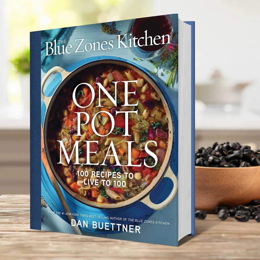 This cookbook features 100 quick and easy recipes inspired by the blue zones The book cover of Dan Buettner's cookbook, “The Blue Zones Kitchen One Pot Meals: 100 Recipes to Live to 100”
