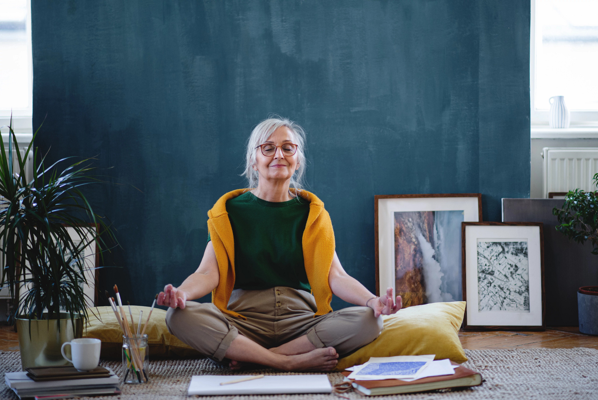 Senior woman sitting and relaxing indoors at home, doing yoga.