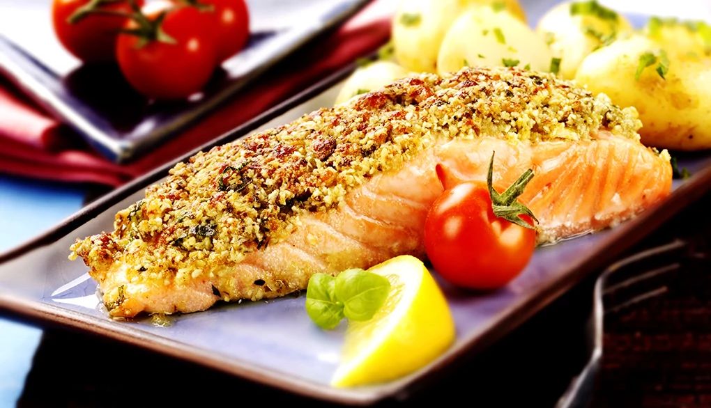 Eating fish may protect your brain against air pollution A close-up view of baked salmon with a pesto crust on a plate