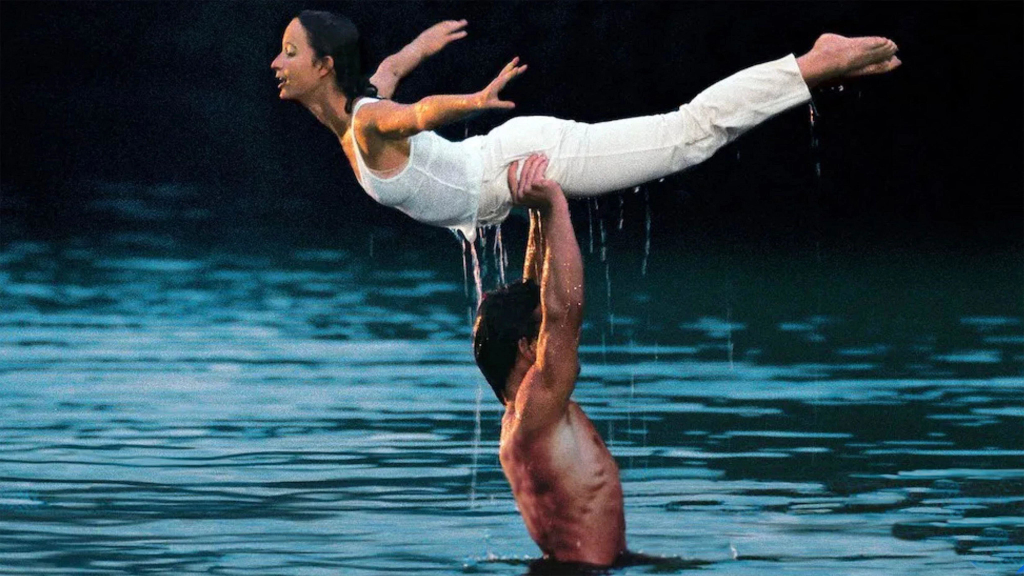 Patrick Swayze and Jennifer Grey performing a graceful water lift during an outdoor dance in a lake in the film Dirty Dancing