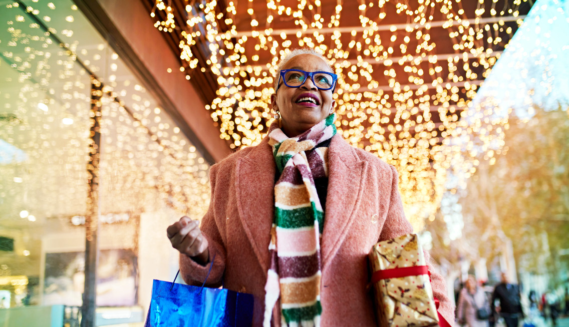 a woman carries wrapped presents down a street