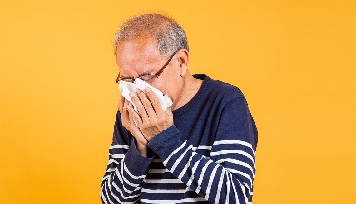6 Ways to Get Relief from Seasonal Allergies and older man sneezing into a tissue in front of a yellow background