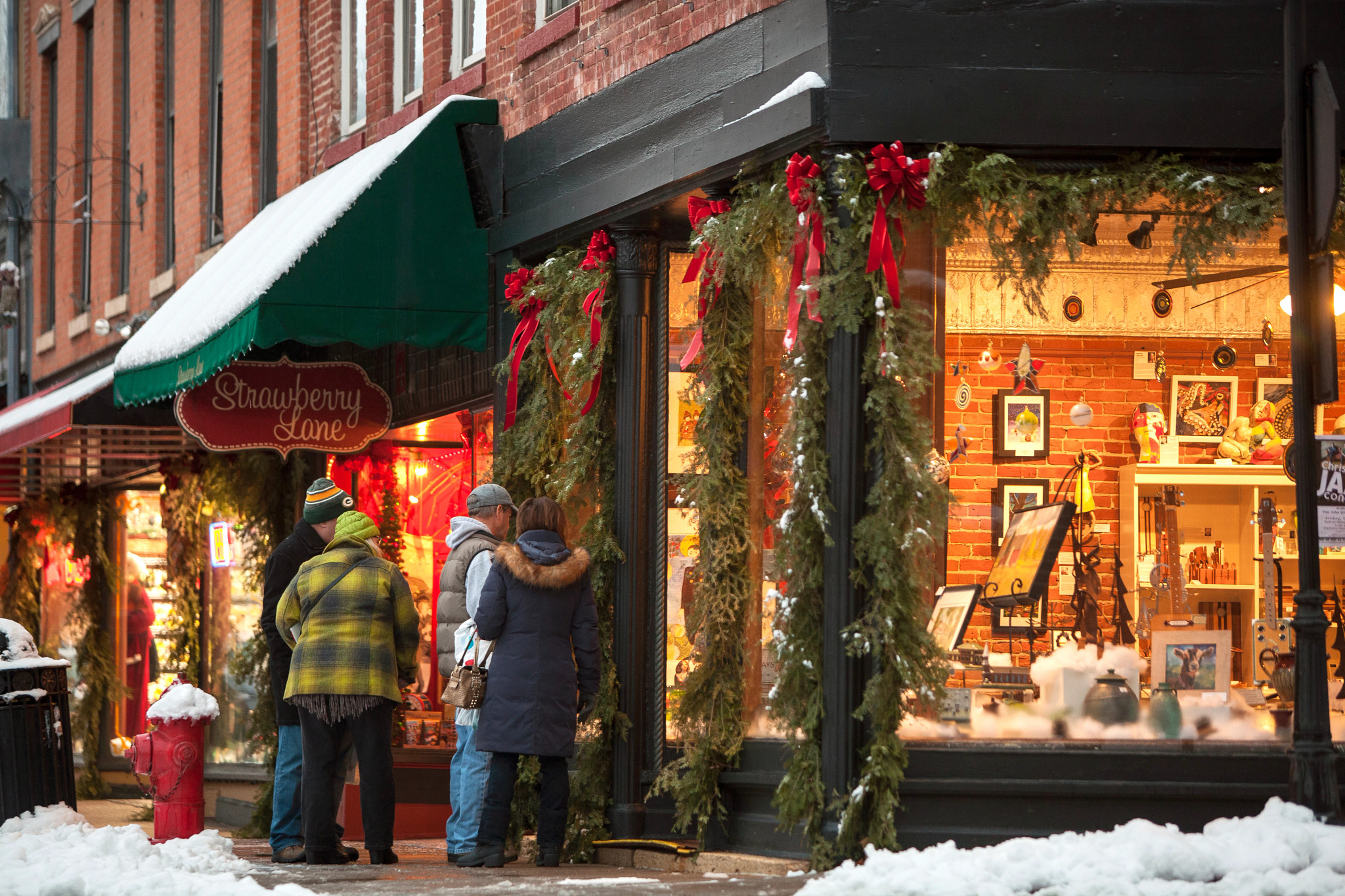 people looking at a storefront with holiday decorations