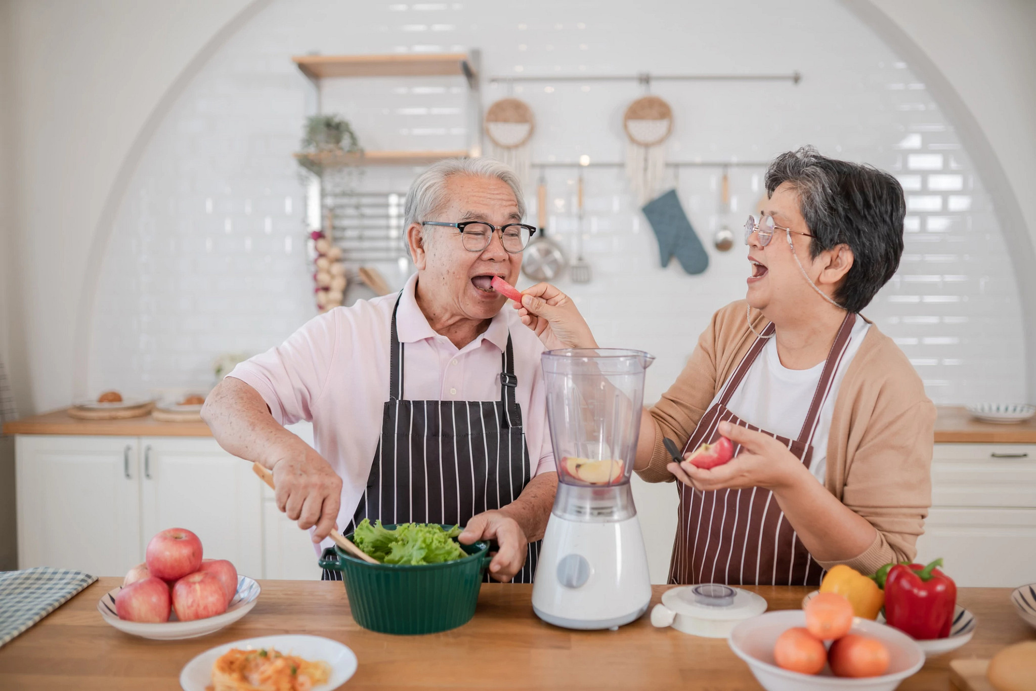 Two people in kitchen cooking looking at tablet.