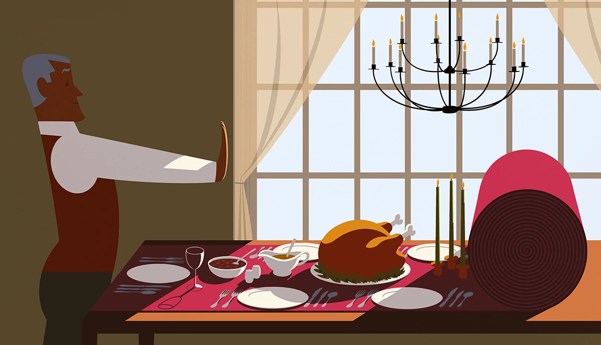 a person rolls a red carpet across a table, revealing a holiday feast