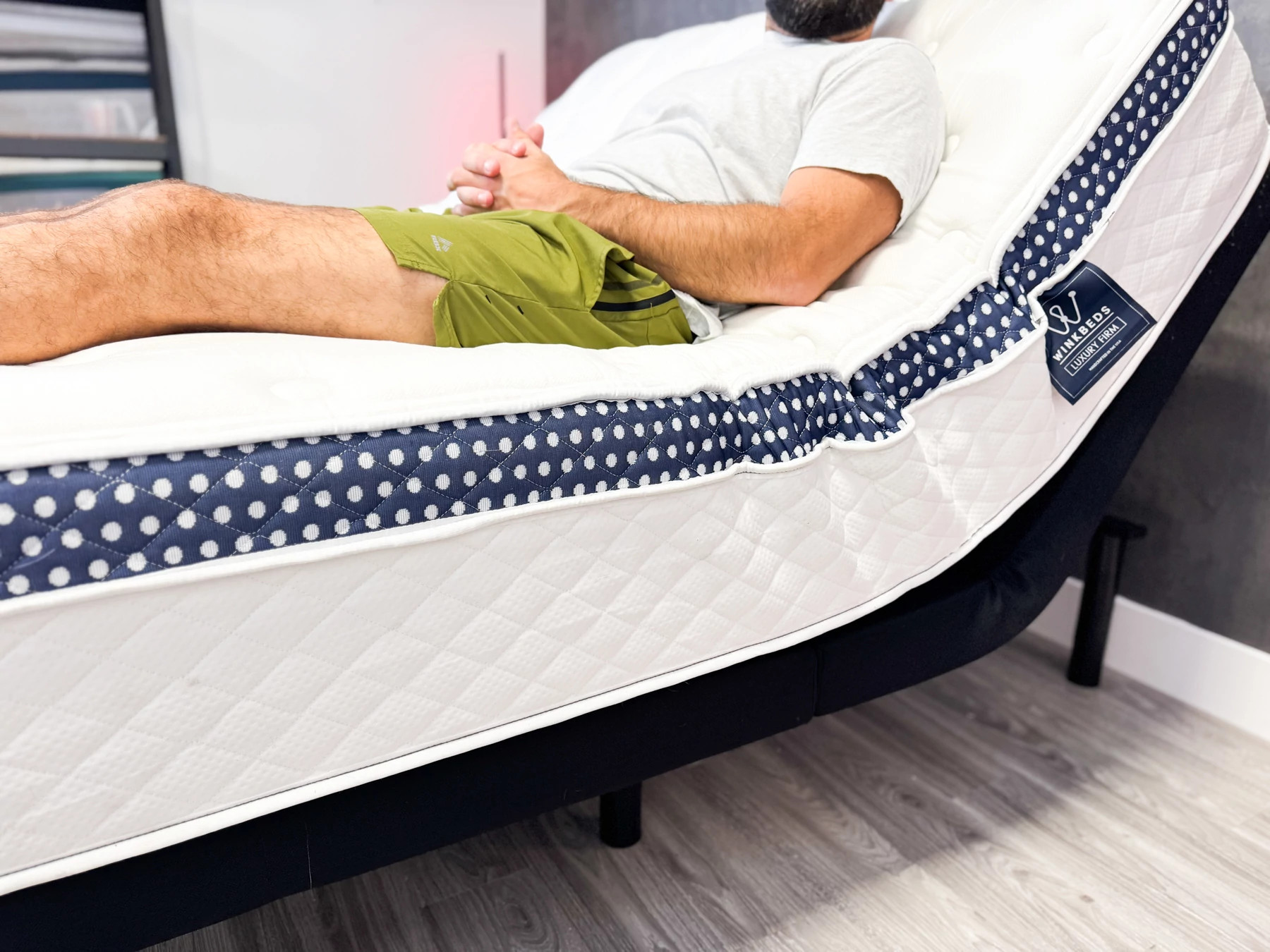 A man sitting on the WinkBed mattress on an adjustable base.