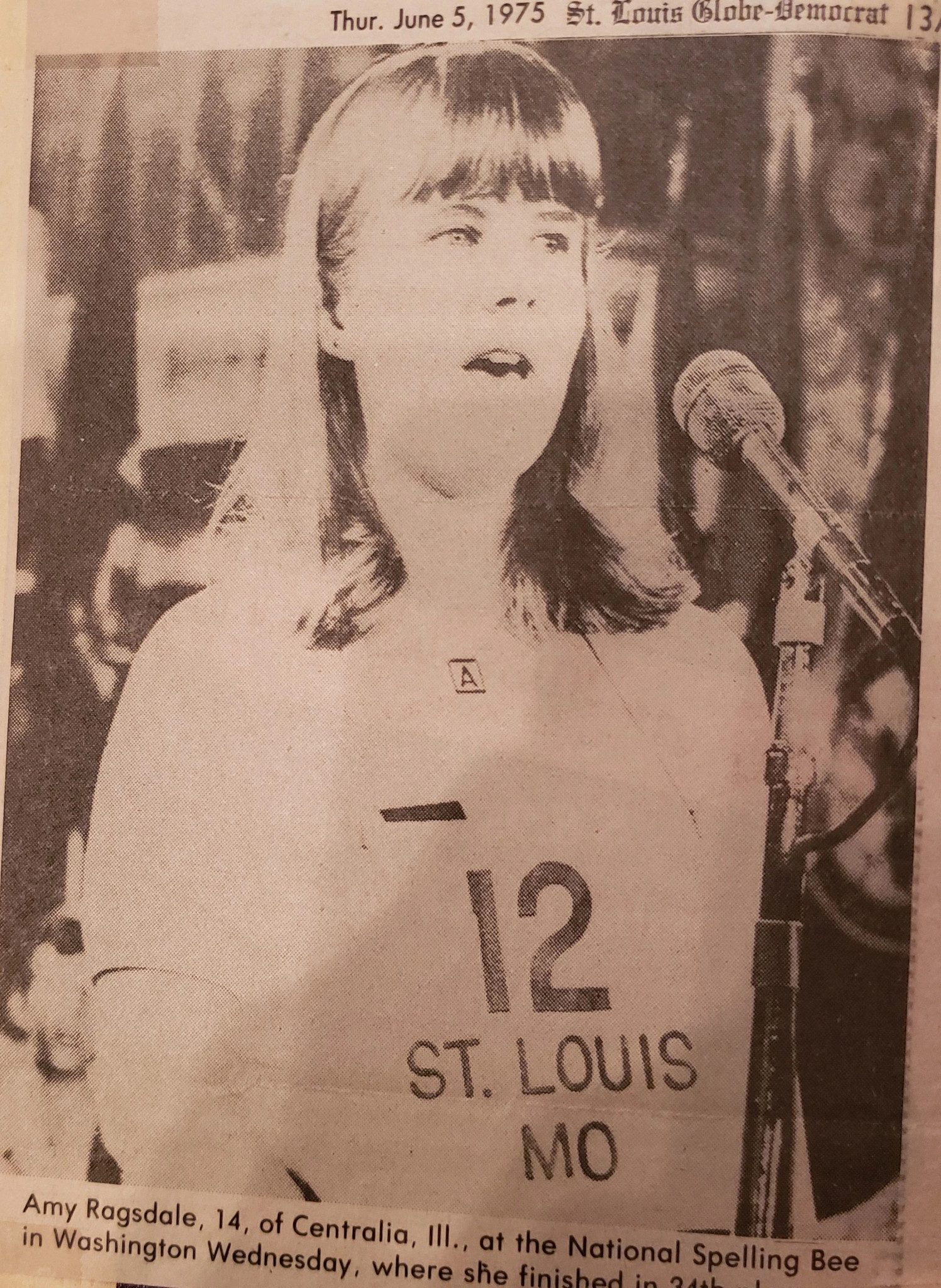A clipping from a June 1975 issue of the St. Louis Globe-Democrat highlights Amy Blakely’s appearance at the Scripps-Howard National Spelling Bee in Washington, D.C. Blakely is shown competing in a photo from the clipping.