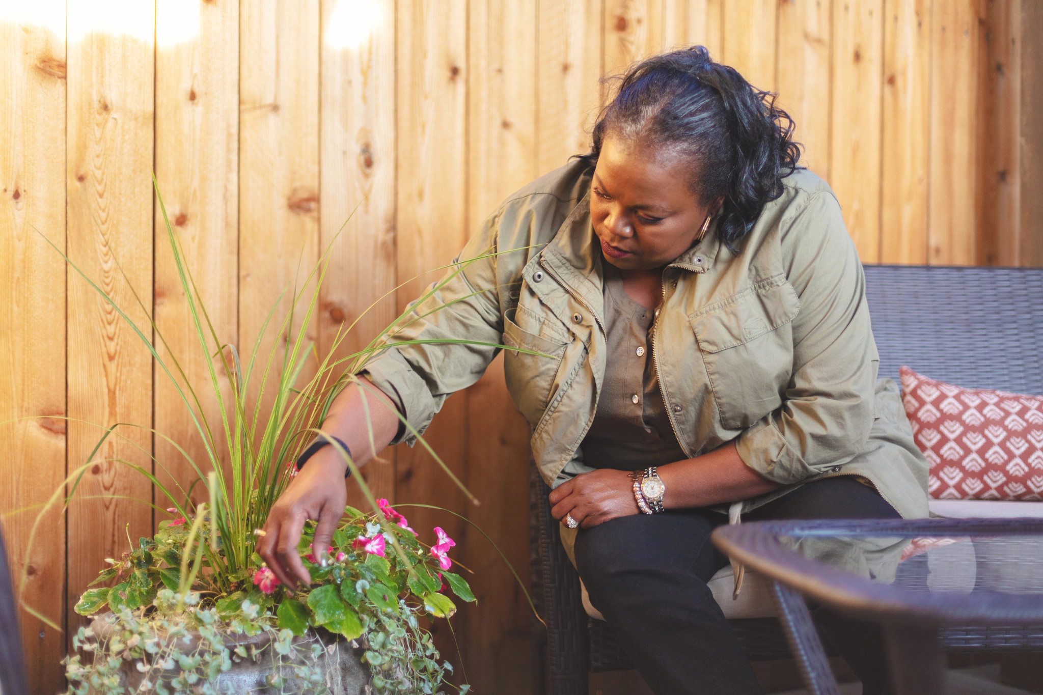 woman prunes a plant on her patio
