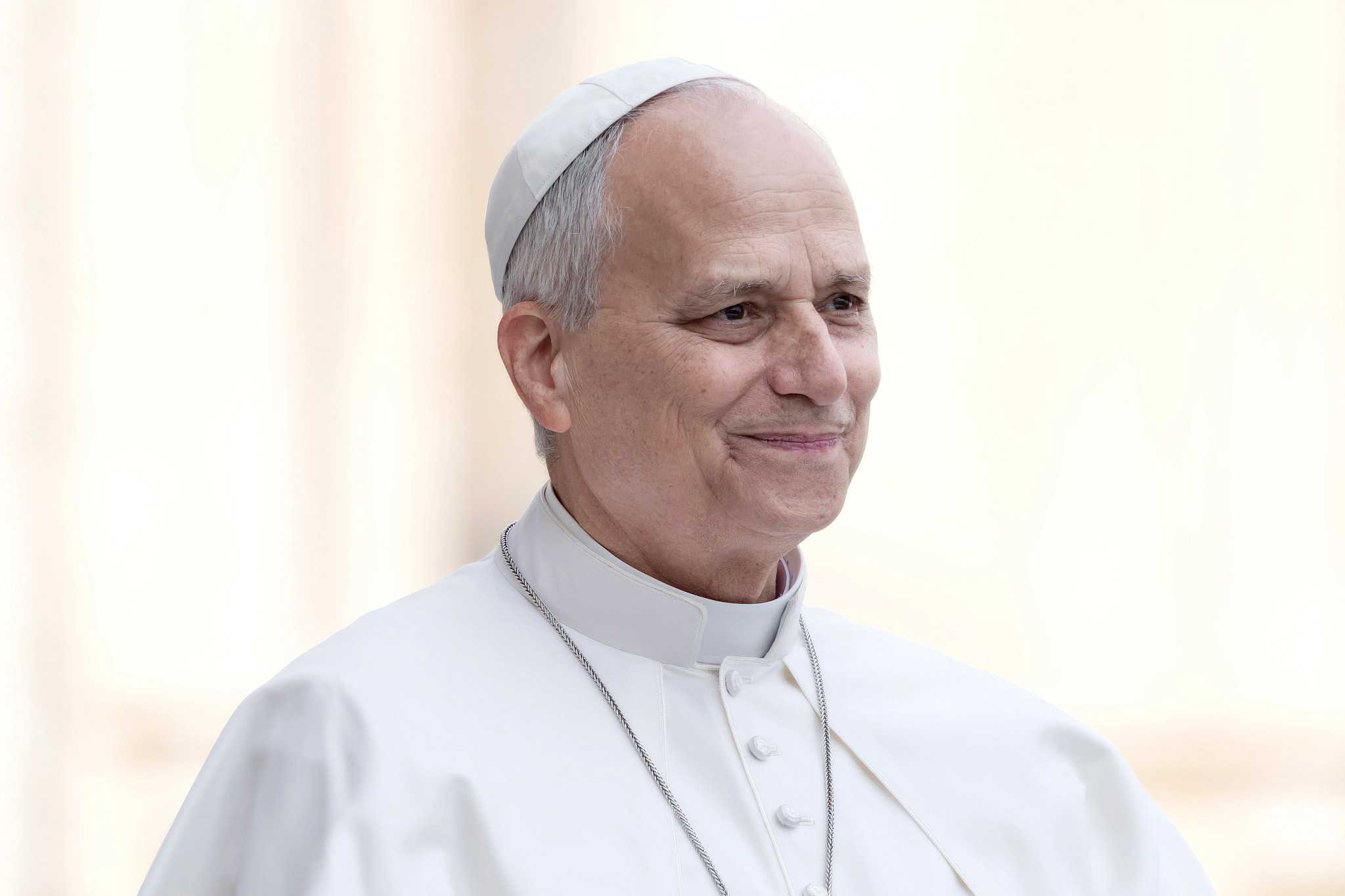 Pope Leo smiling while wearing white papal vestments and a zucchetto.