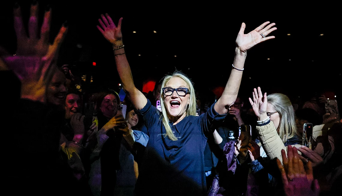 Mel Robbins mel robbins puts her arms up to wave as she walks through a crowd