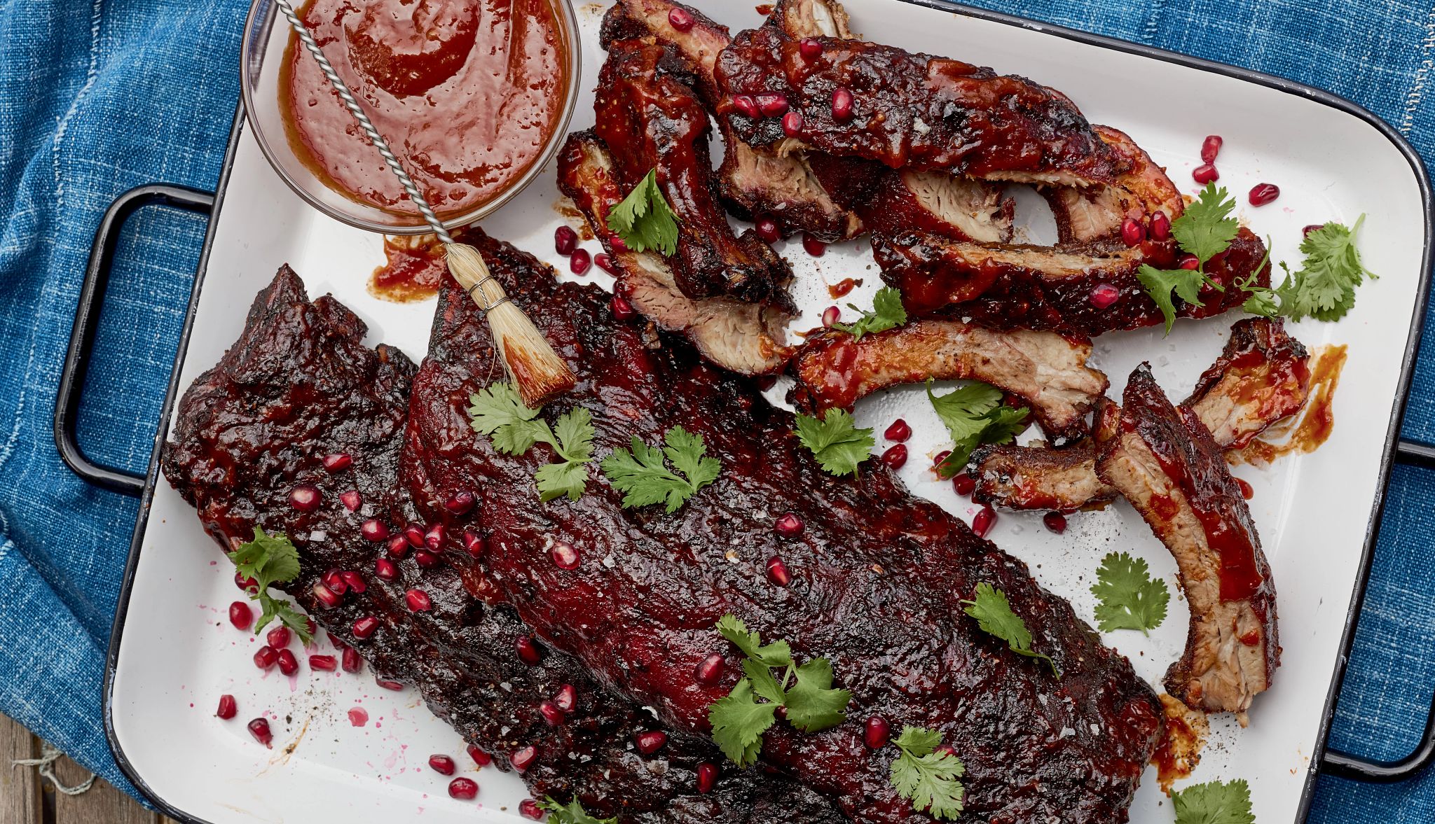 Smoked baby back ribs with chipotle pomegranate bbq sauce Smoked ribs and small bowl of sauce on plate