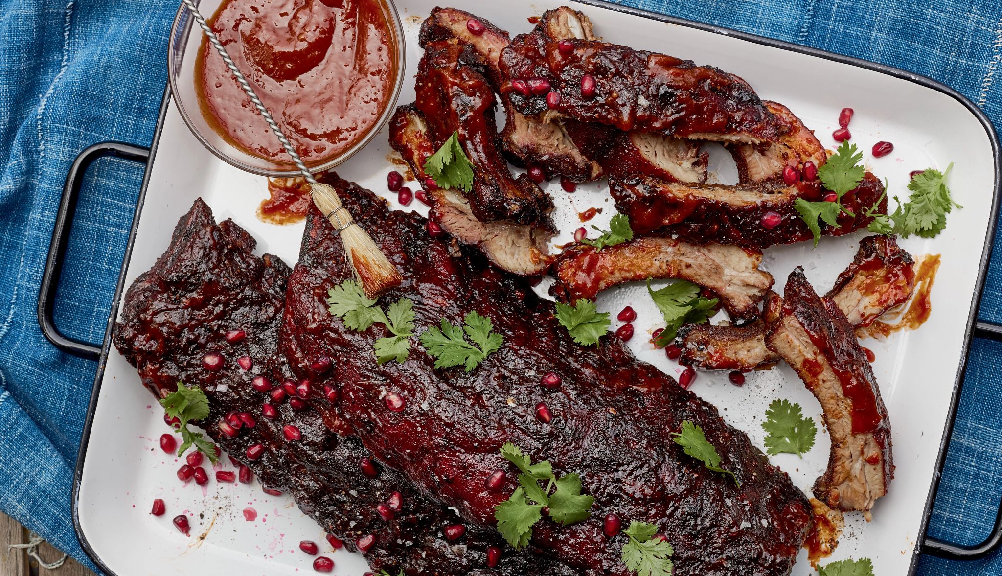 Smoked baby back ribs with chipotle pomegranate bbq sauce Smoked ribs and small bowl of sauce on plate