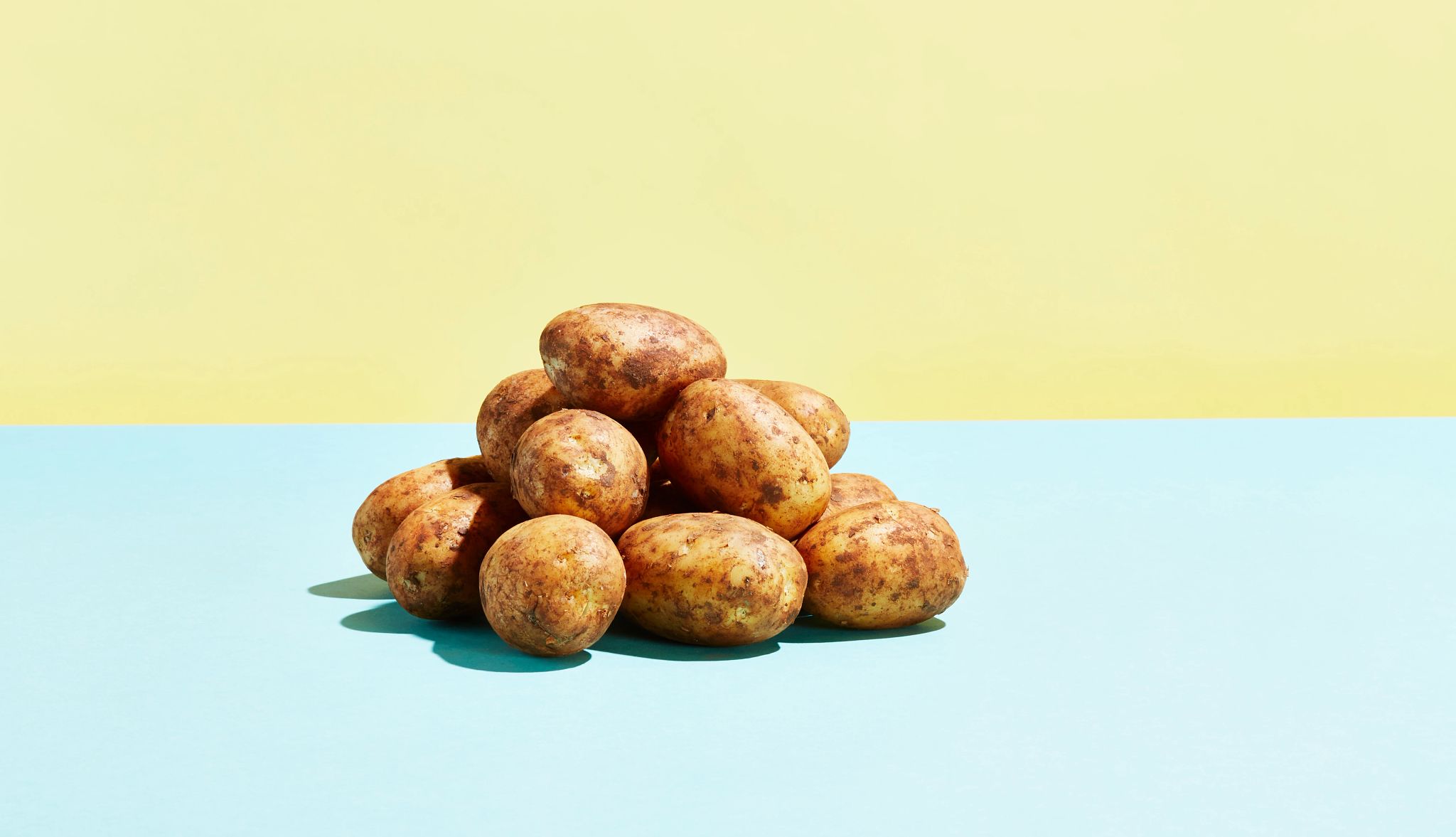 Health Benefits of Potatoes pile of potatoes on a blue and yellow background