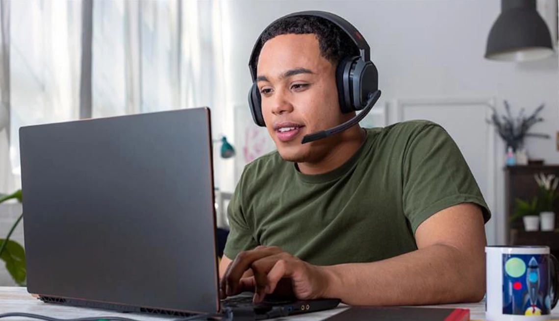 Man wearing a headset working at his laptop offering tech support to a client