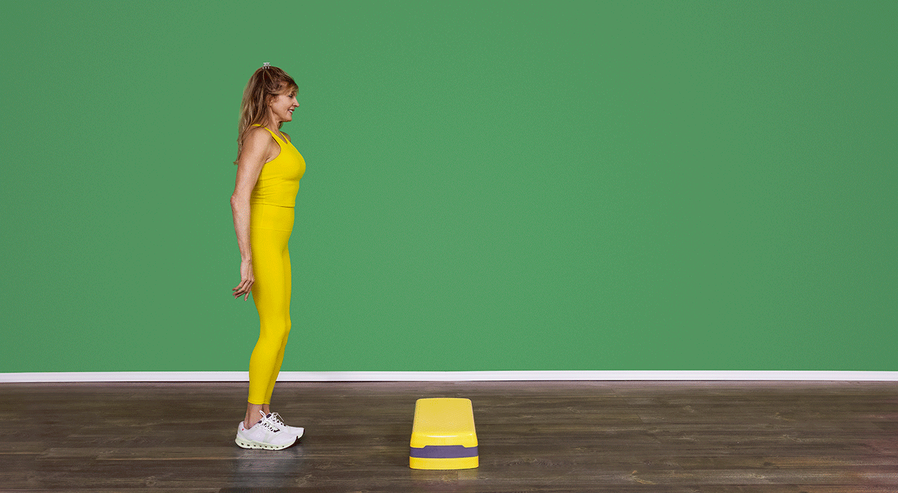 Kathy Smith in front of an aerobic step platform in a fitness studio performing a step-up exercise