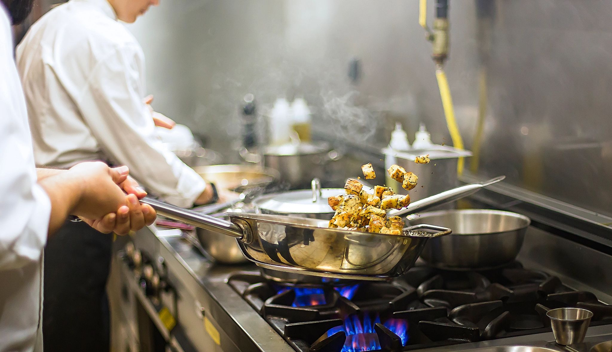 Close up shot of a chef searing food on a pan Close up shot of a chef searing food on a pan