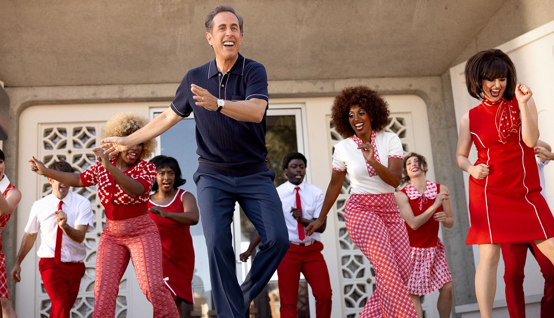 Jerry Seinfeld dancing with other people in a scene from Unfrosted