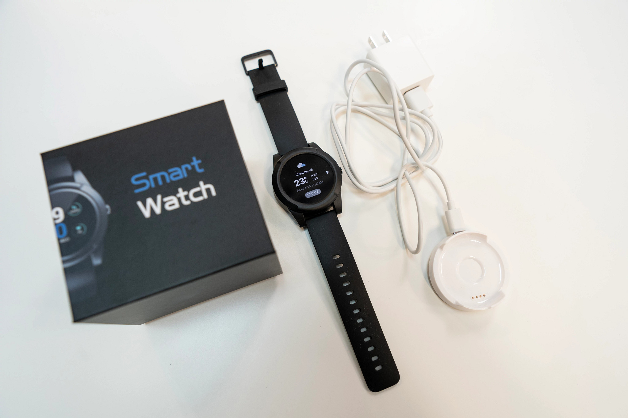 The Lifefone Safe Watch Active next to its packaging and charger on a white table