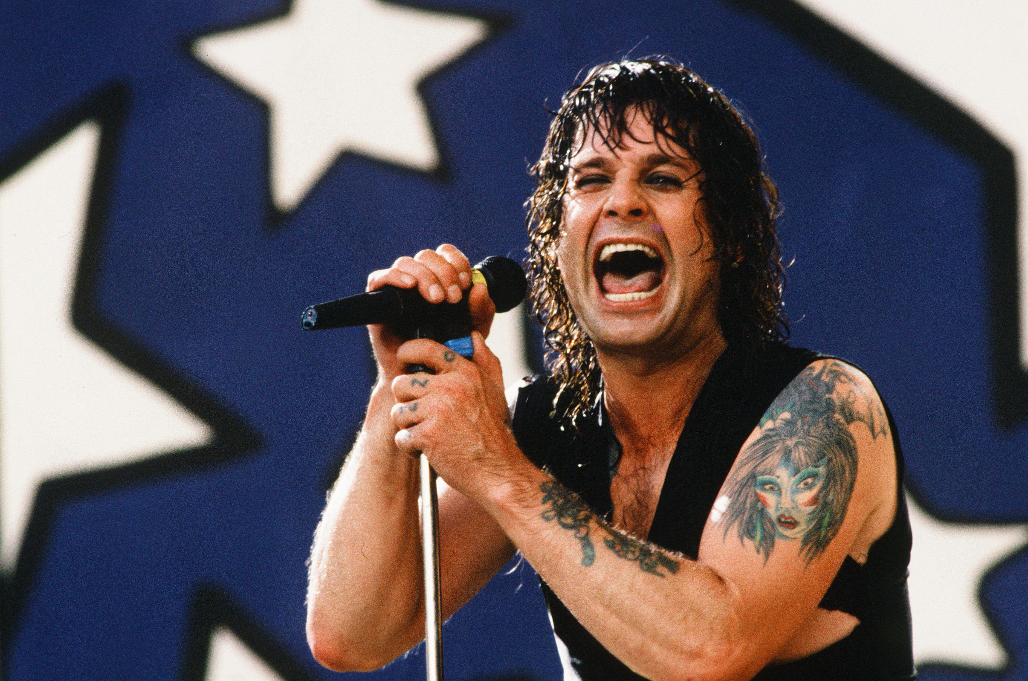 Ozzy Osbourne holds a microphone on stage