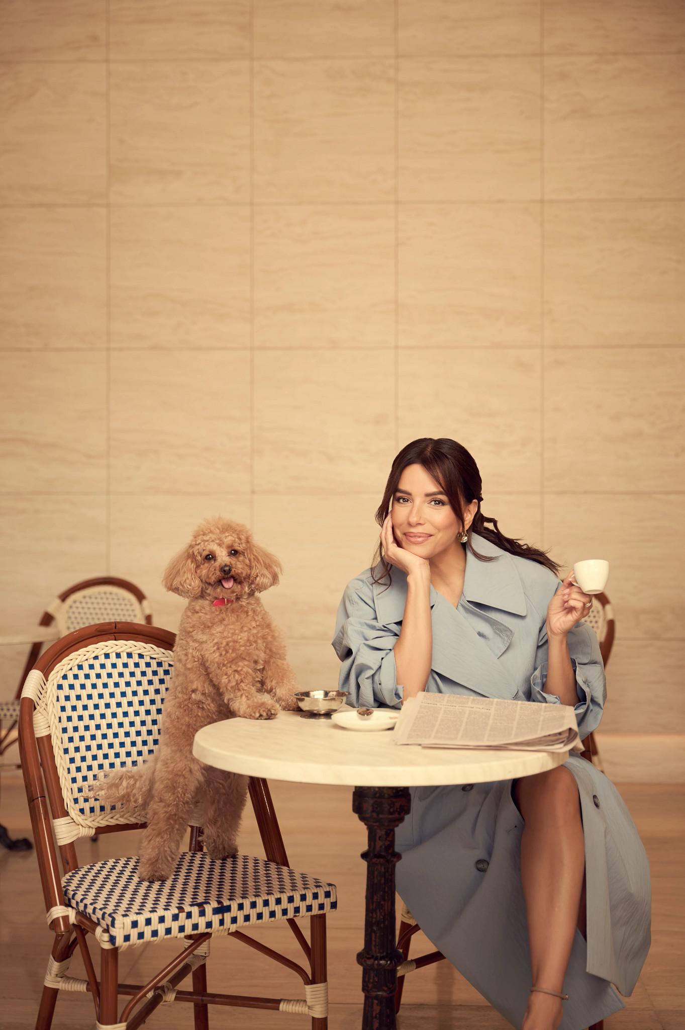 eva longoria posing at a cafe table with an esspresso cup, newspaper and small dog