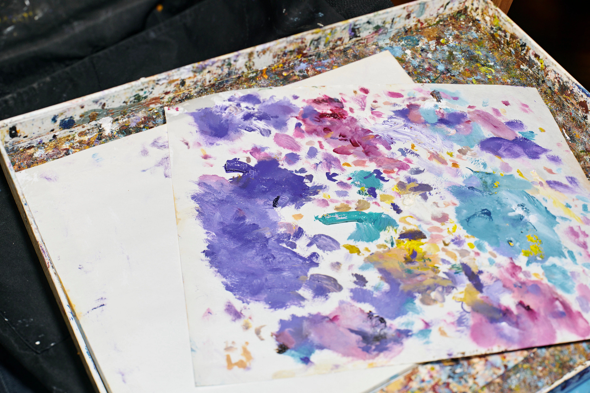 spotches of paint on a sheet of paper that is resting on a painters palette