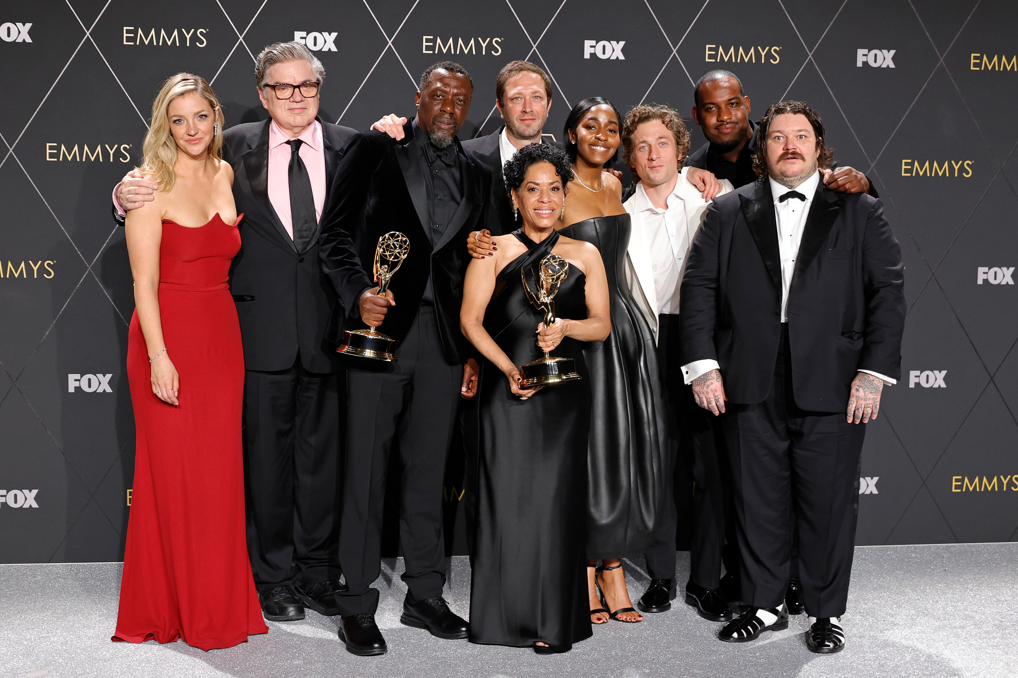 Oliver Platt and fellow cast members holding Emmy statuettes in front of Emmys and Fox backdrop