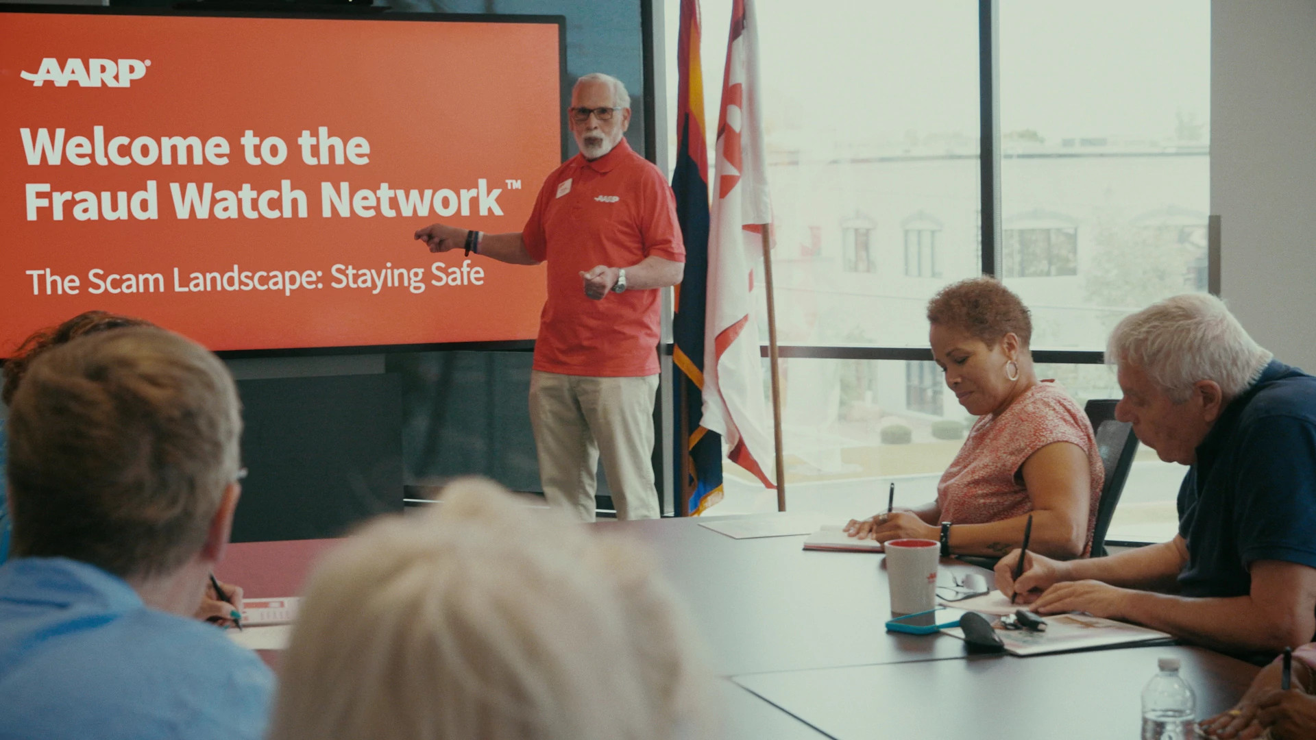 aarp volunteer giving a presentation about fraud to a board room