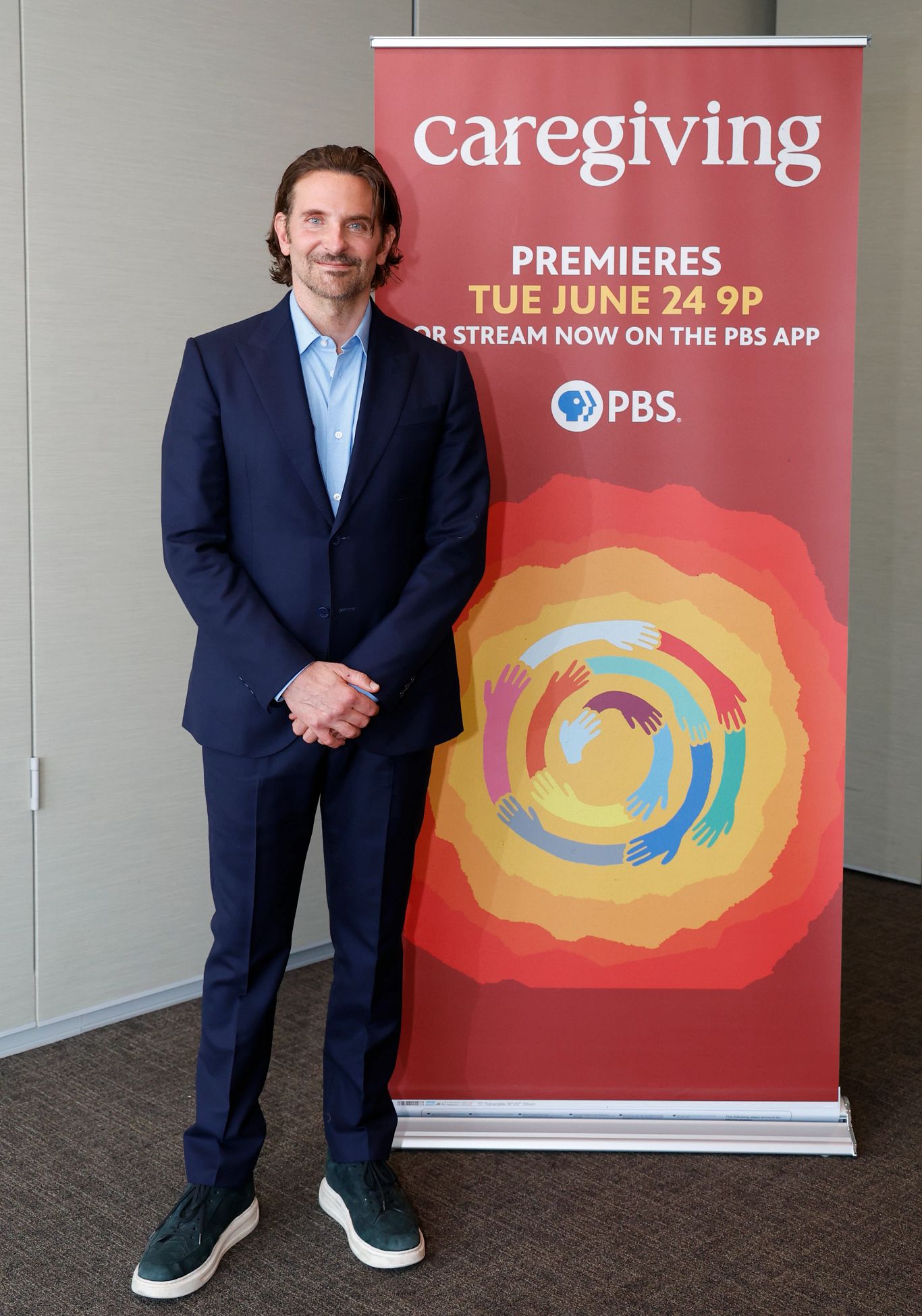 Bradley Cooper bradley cooper stands in front of a banner for his caregiving documentary