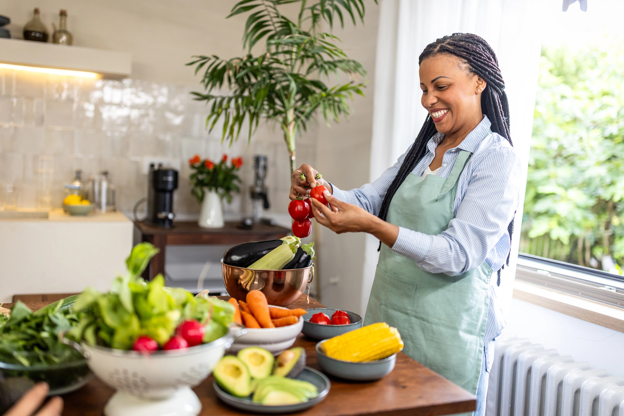 Young African-American woman preparing delicious vegetables in the bright and modern kitchen.