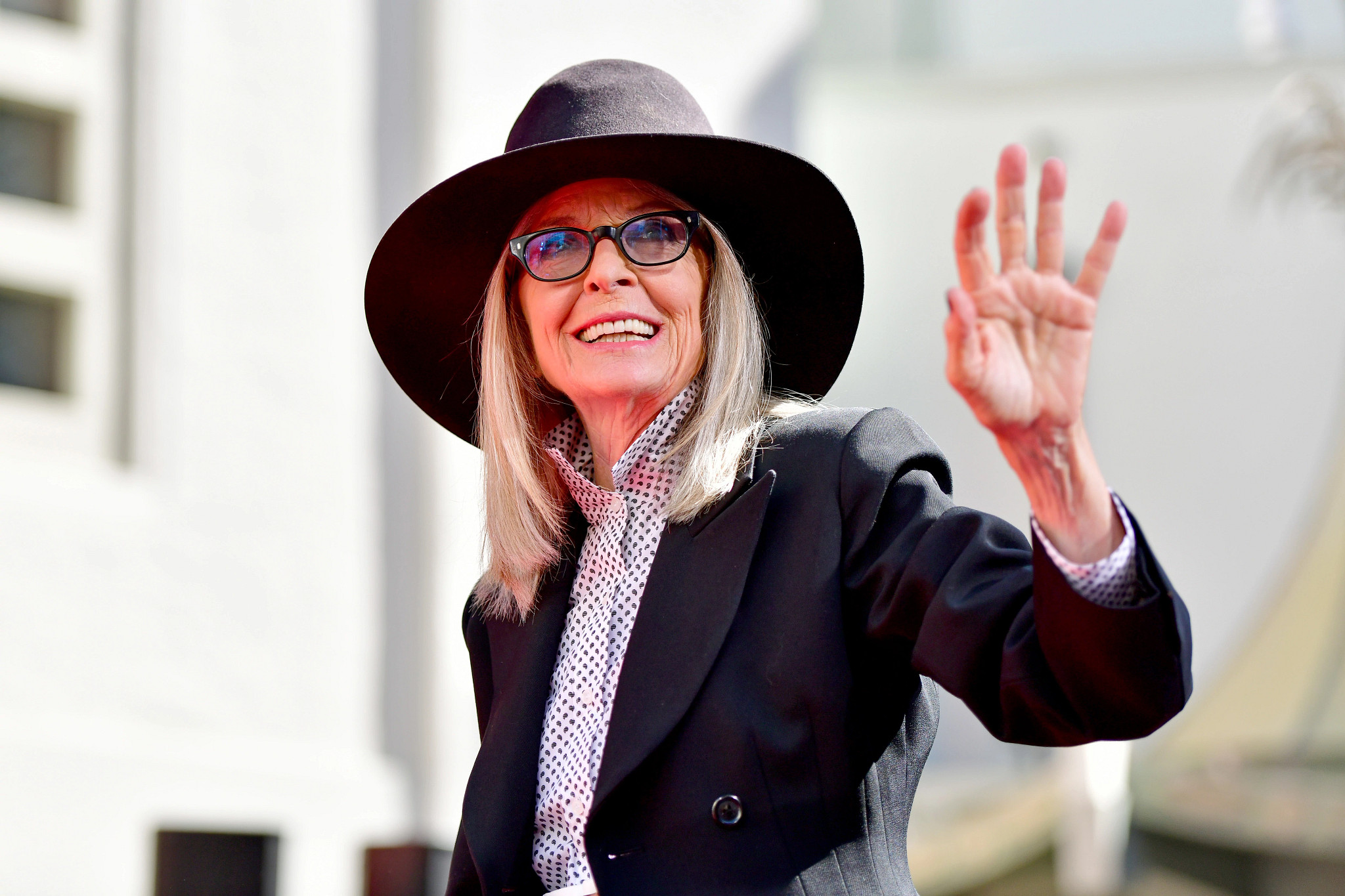 diane keaton in black hat and glasses waving