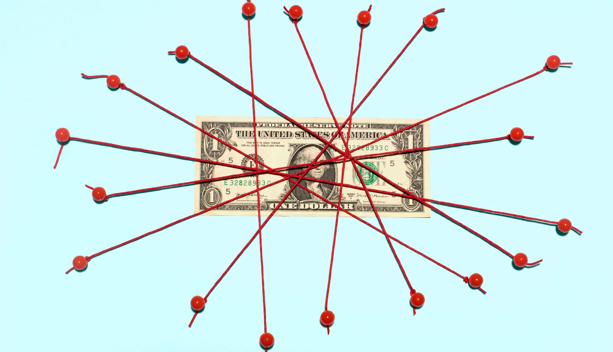 a dollar bill with red thread over it